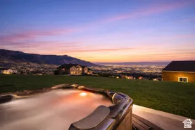 Outdoor hot tub with integrated lighting, surrounded by a concrete patio and expansive lawn