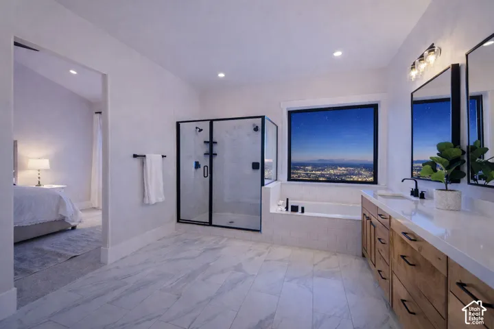 Spacious bathroom featuring marble-look tile flooring, a glass-enclosed shower, built-in soaking tub, and a double vanity with wood-finish cabinetry