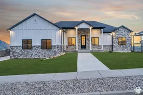 Contemporary exterior featuring board and batten siding, stone accents, black-trimmed windows, a covered entry with columns, and a concrete walkway
