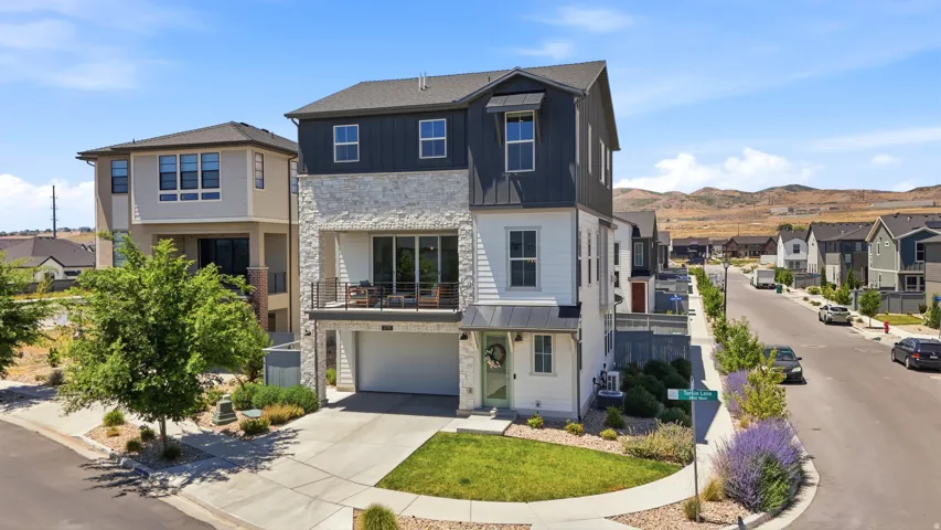 Contemporary architecture with stone and siding exterior, private balcony, integrated garage, and landscaped front yard