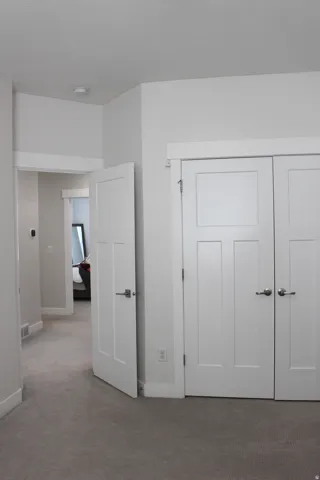 Light gray carpeted flooring, white trim, and white paneled doors