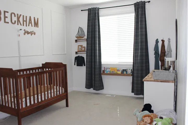 Wall with decorative molding, large window with blinds, window-length shelving, recessed lighting, and light-colored carpeting