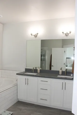 Dual vanity with white cabinetry, matte gray countertops, and undermount sinks