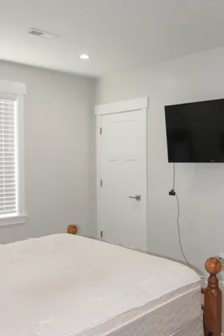 Recessed ceiling lighting, white interior door, window with white blinds, and light-toned walls