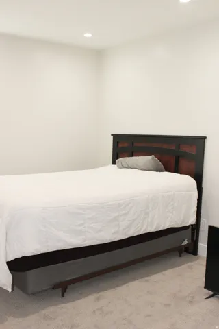 Recessed lighting illuminates the room, featuring light-toned carpet flooring and neutral wall finishes
