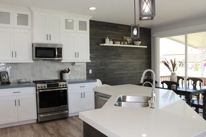 White shaker cabinetry, stainless steel appliances, solid surface countertops, wood-finish flooring, and a large sliding glass door