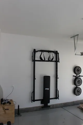 Smooth concrete floor with a wall-mounted workout station and weight plate storage