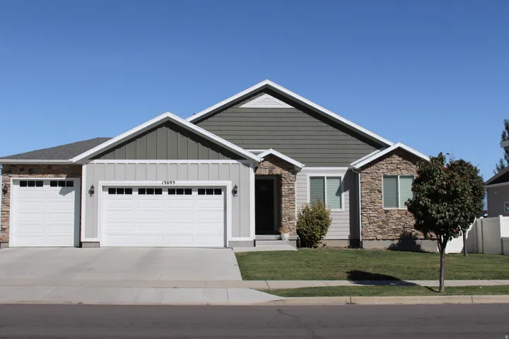 Exterior featuring stone and siding facade, attached two-car garage, separate single-car garage, concrete driveway, and manicured lawn