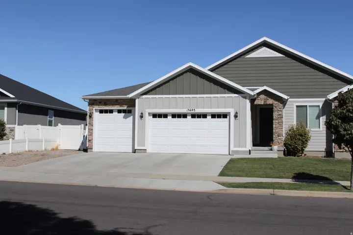 Exterior featuring a stone and siding facade, attached two-car garage, and manicured lawn