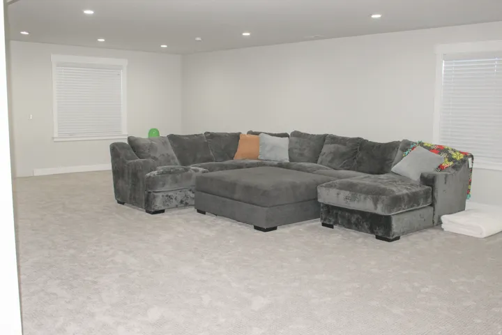 Recessed lighting illuminates a spacious room featuring light-toned carpeting and neutral wall colors