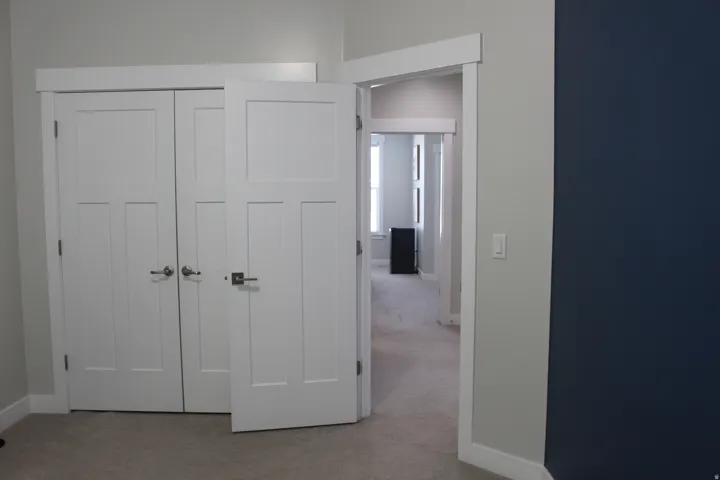 White paneled doors with contrasting hardware, light grey wall paint, and plush carpet flooring