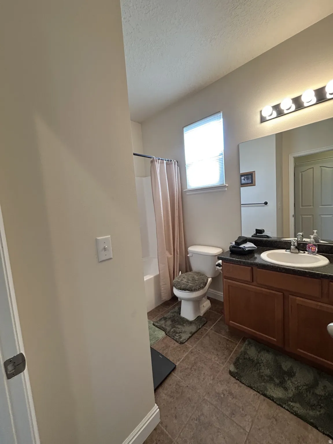 Bathroom featuring a single vanity, integrated sink, wood-finish cabinetry & tiled flooring