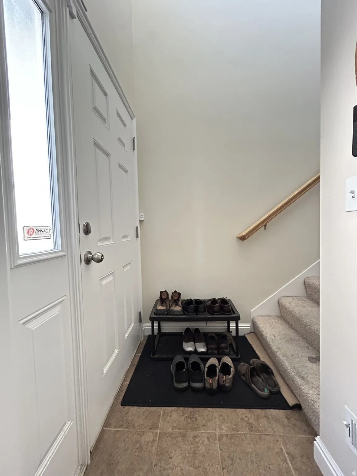 White panel door with satin nickel hardware & neutral color tile floor.