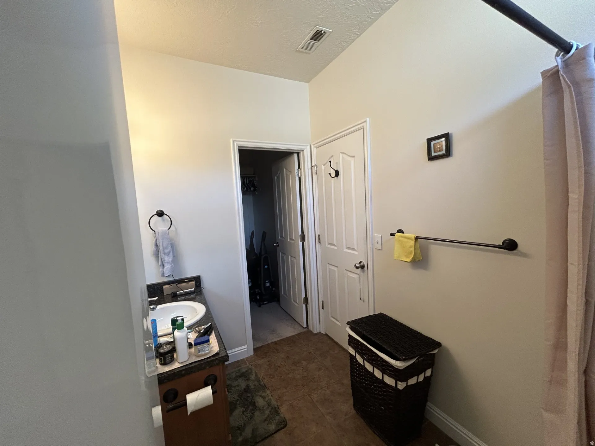 Vanity with integrated sink and dark countertop, wood-finish flooring & a white paneled door.