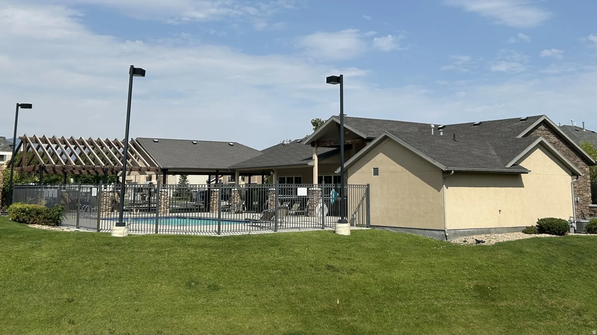 Outdoor swimming pool enclosed by black metal fencing south of the clubhouse/exercise building.