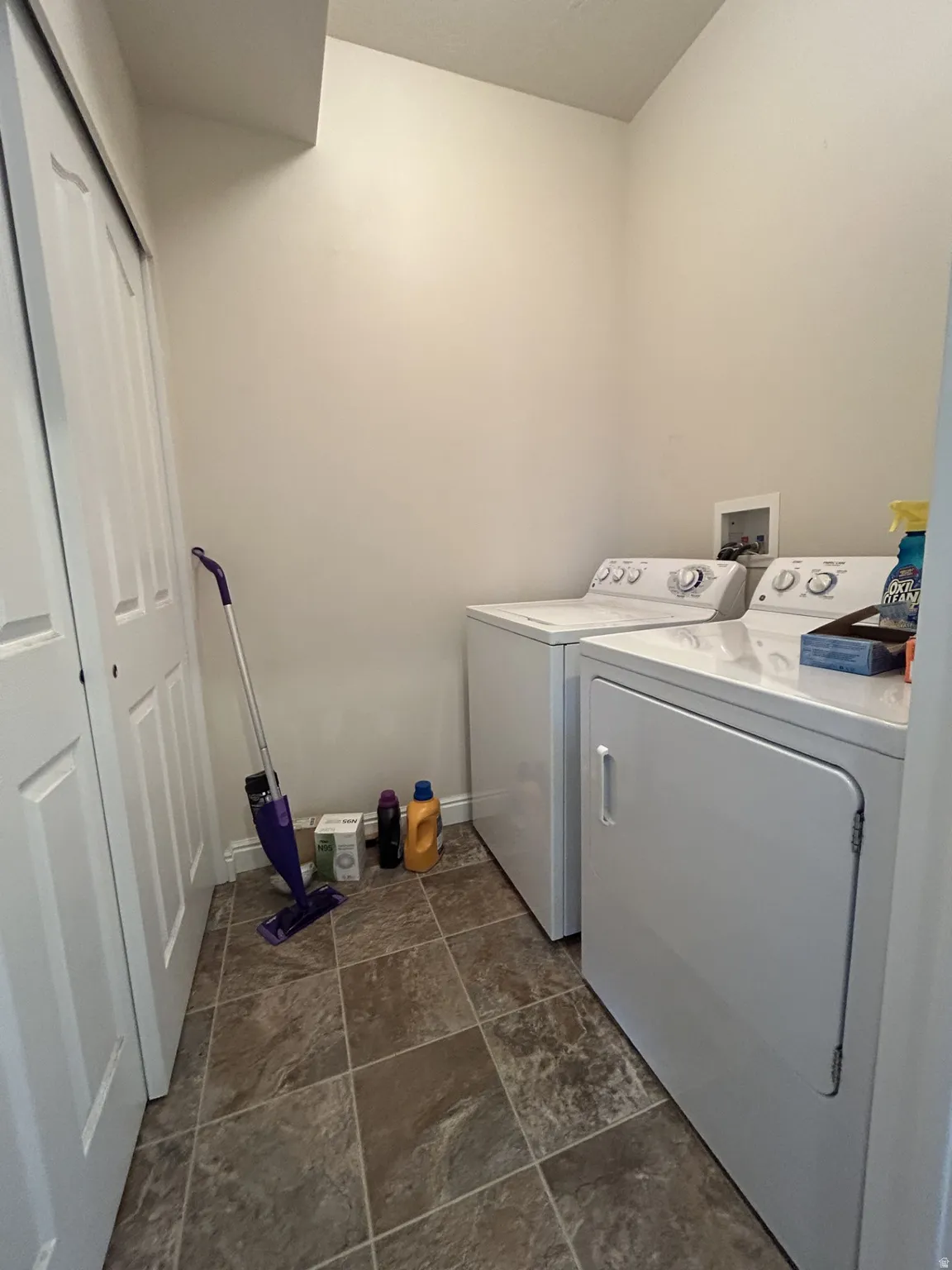 Dedicated laundry area featuring a washer & dryer, durable tile flooring & a storage closet with sliding doors.