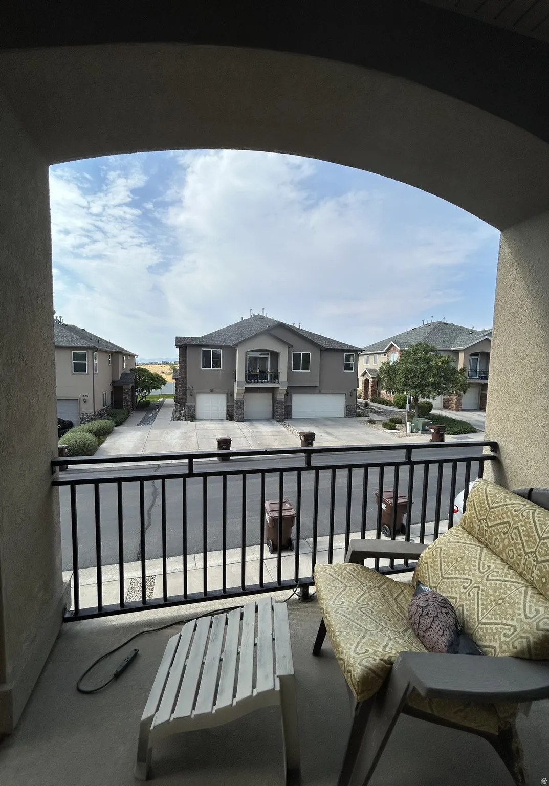 South facing balcony with dark metal railing, arched entryway & neutral-toned exterior finish