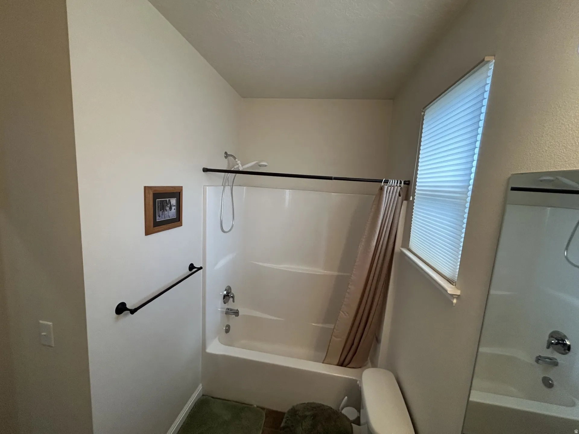 Tub/shower combination with chrome fixtures & a window with blinds