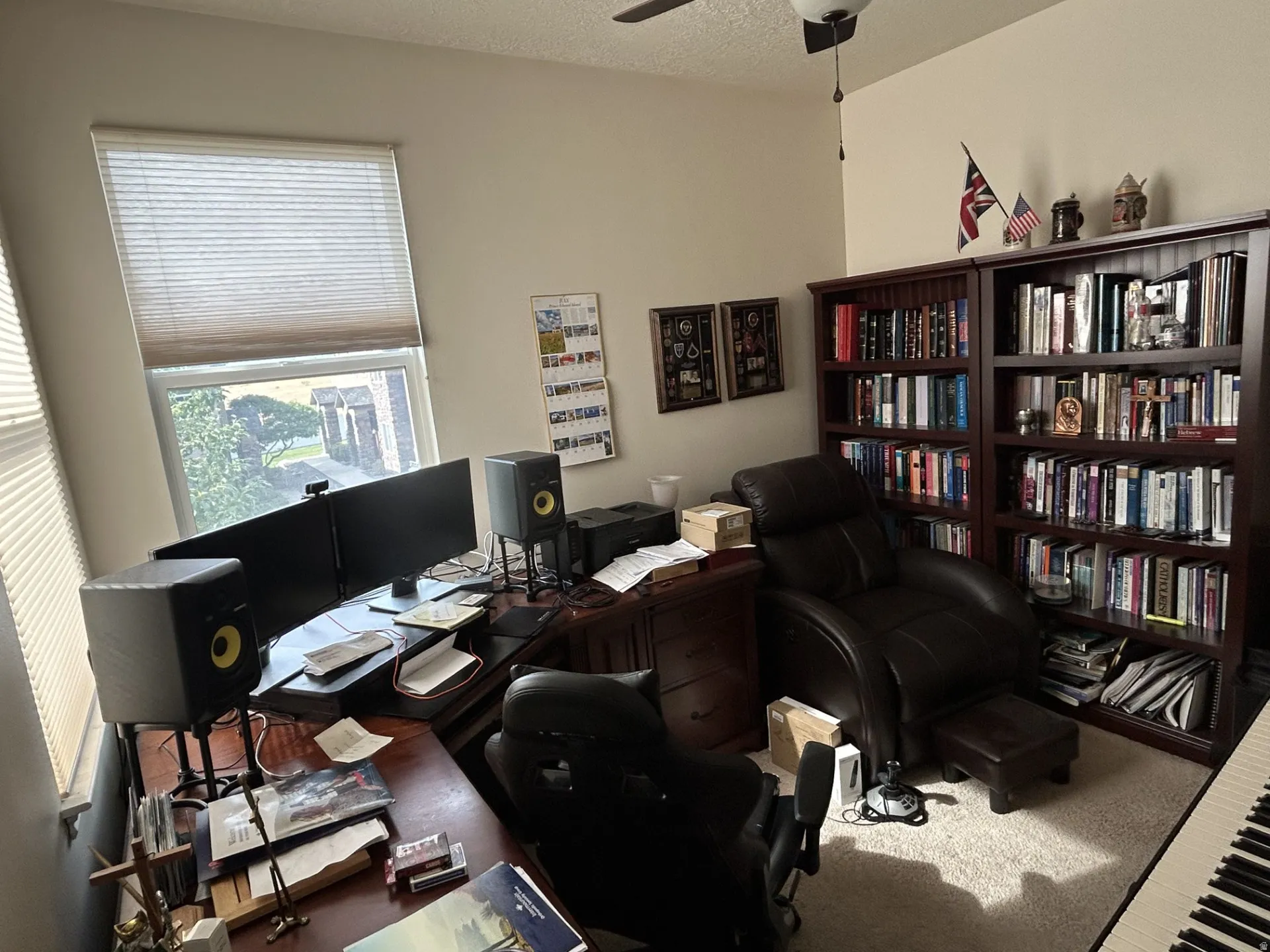 Built-in ceiling fan, full-height built-in bookshelves, and large window with blinds