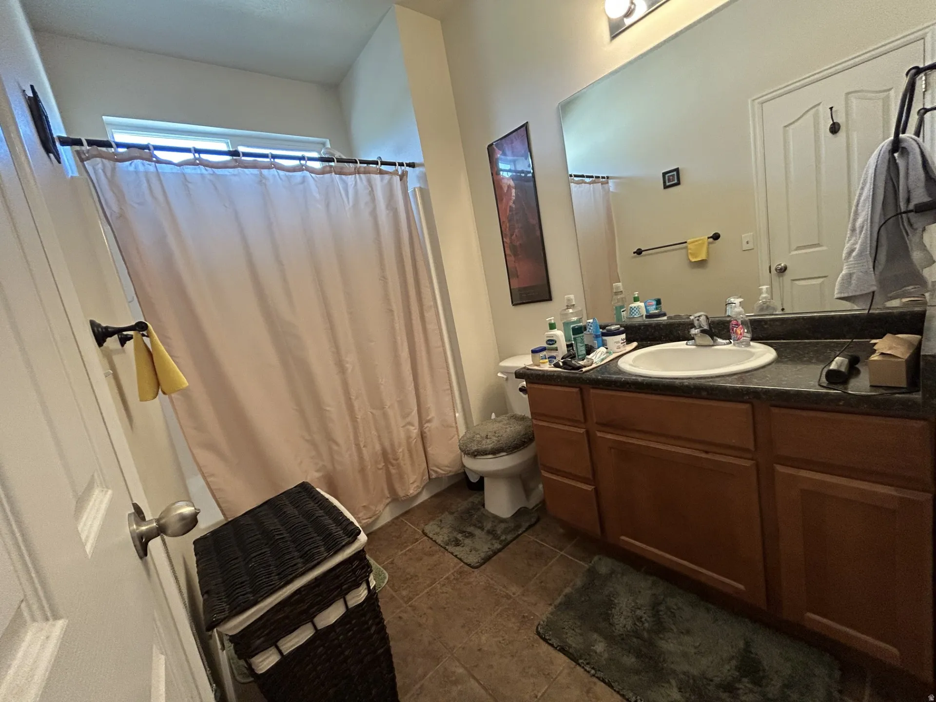 Bathroom featuring a single vanity with a laminate countertop, integrated sink & wood-finish cabinetry