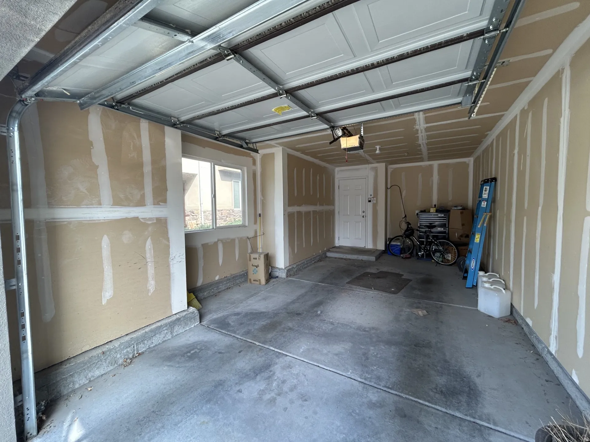 Attached garage with concrete flooring, a side window, storage & an entrance door to the condo.