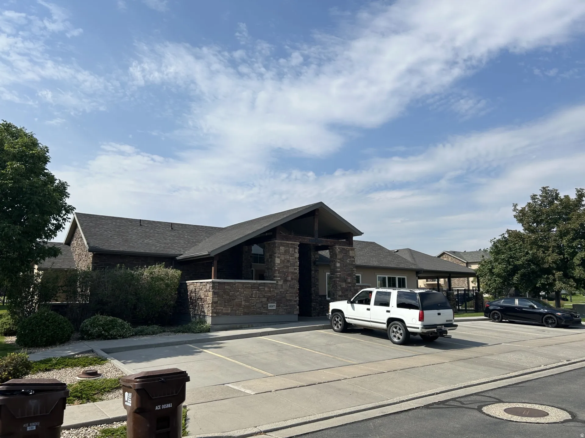 Stone veneer facade with dark shingle roof & covered entryway.
