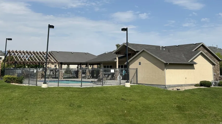 Outdoor swimming pool enclosed by black metal fencing south of the clubhouse/exercise building.