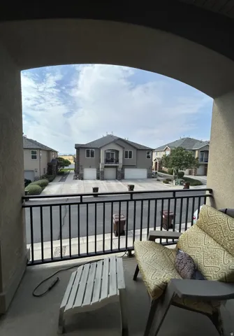 South facing balcony with dark metal railing, arched entryway & neutral-toned exterior finish
