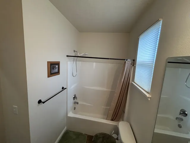 Tub/shower combination with chrome fixtures & a window with blinds