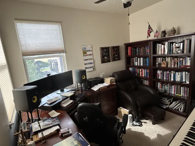 Built-in ceiling fan, full-height built-in bookshelves, and large window with blinds