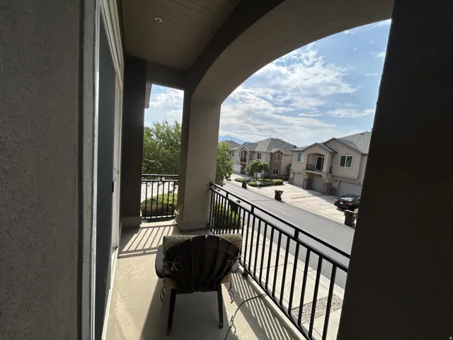 Arched balcony entrance with a concrete floor & black metal railing East view.