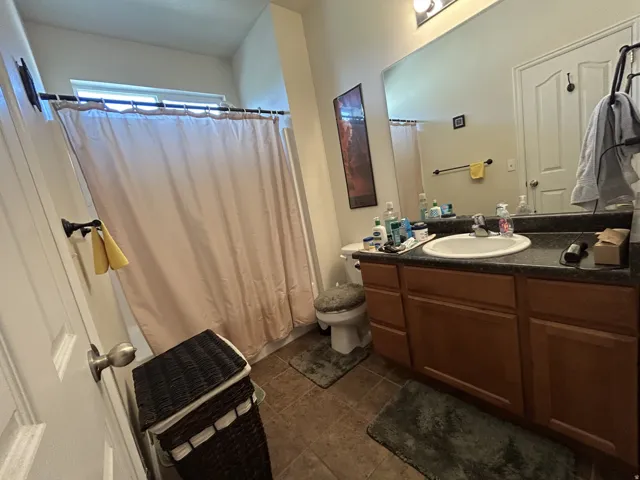 Bathroom featuring a single vanity with a laminate countertop, integrated sink & wood-finish cabinetry