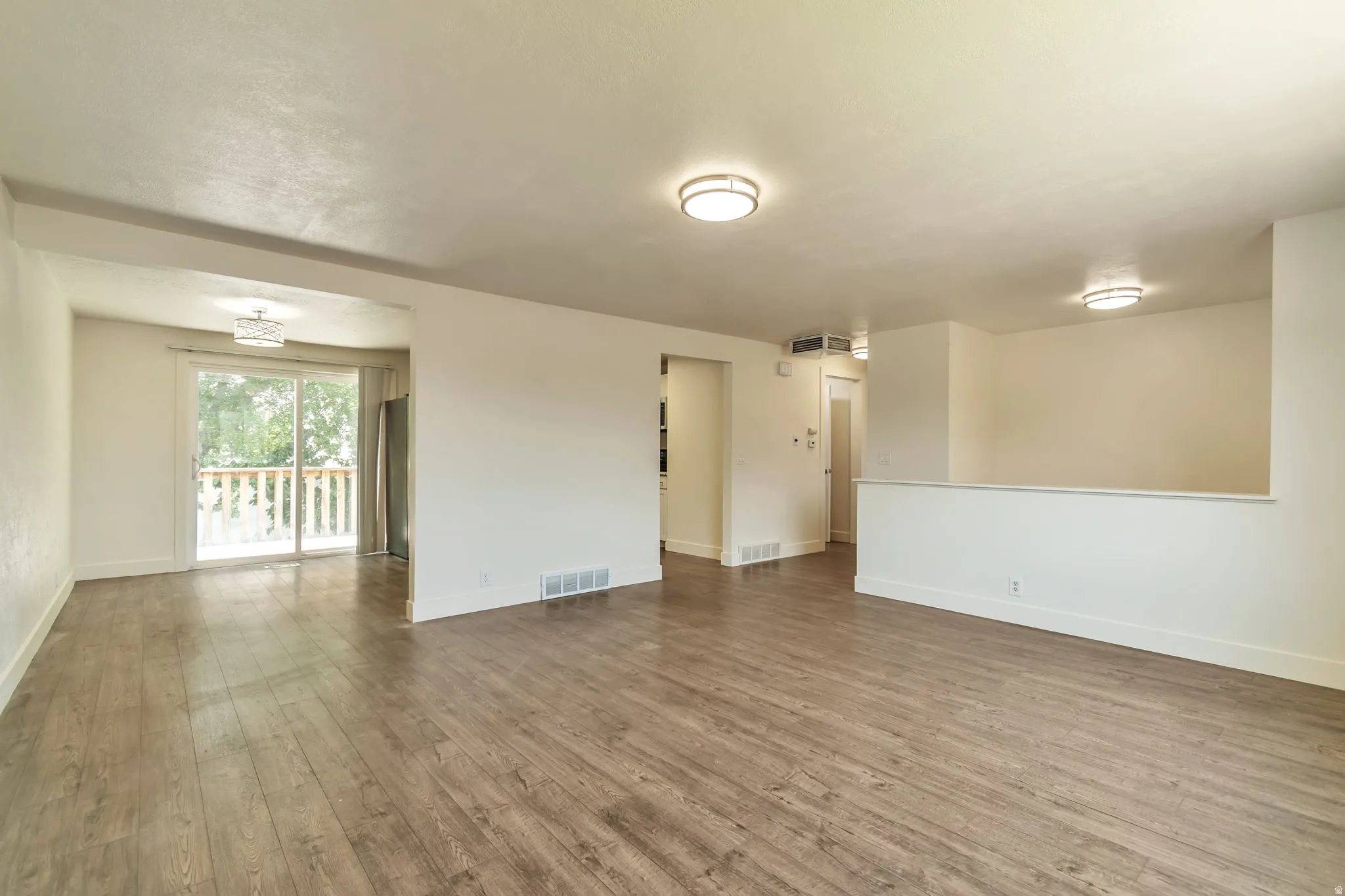 Wood-finish flooring throughout, with a half-wall partition and flush mount lighting fixtures