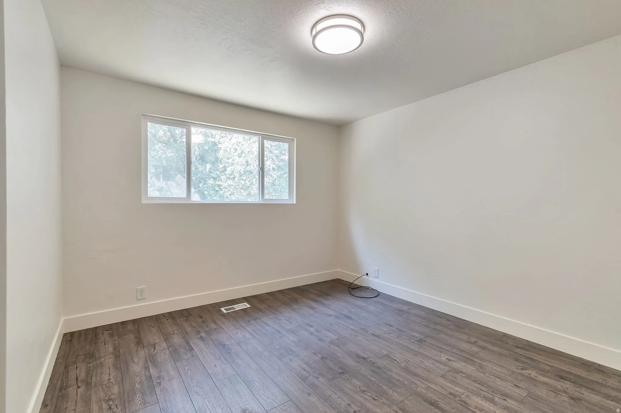 Recessed window, wood-finish flooring, white walls, flush mount ceiling light