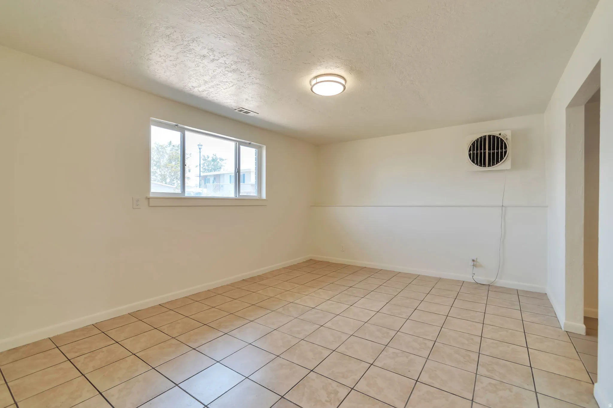 Neutral-toned ceramic tile flooring, white walls, and a multi-pane window