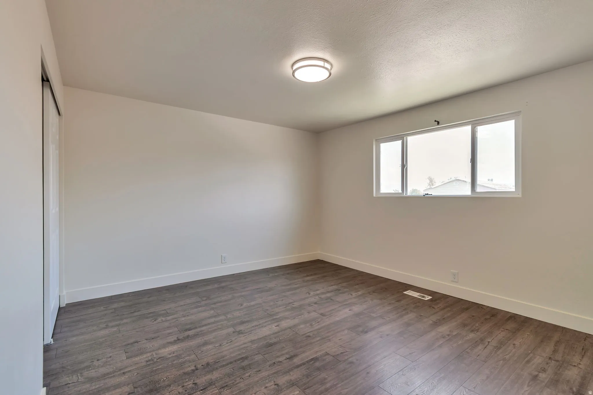 Wood-finish flooring, white walls, and a ceiling-mounted light fixture