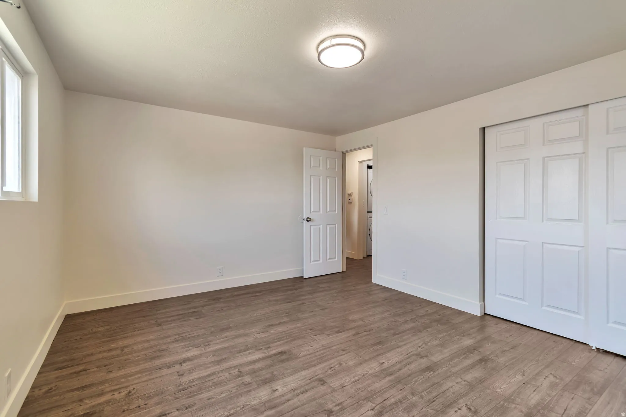 Wood-finish flooring, white walls, and a window providing natural light