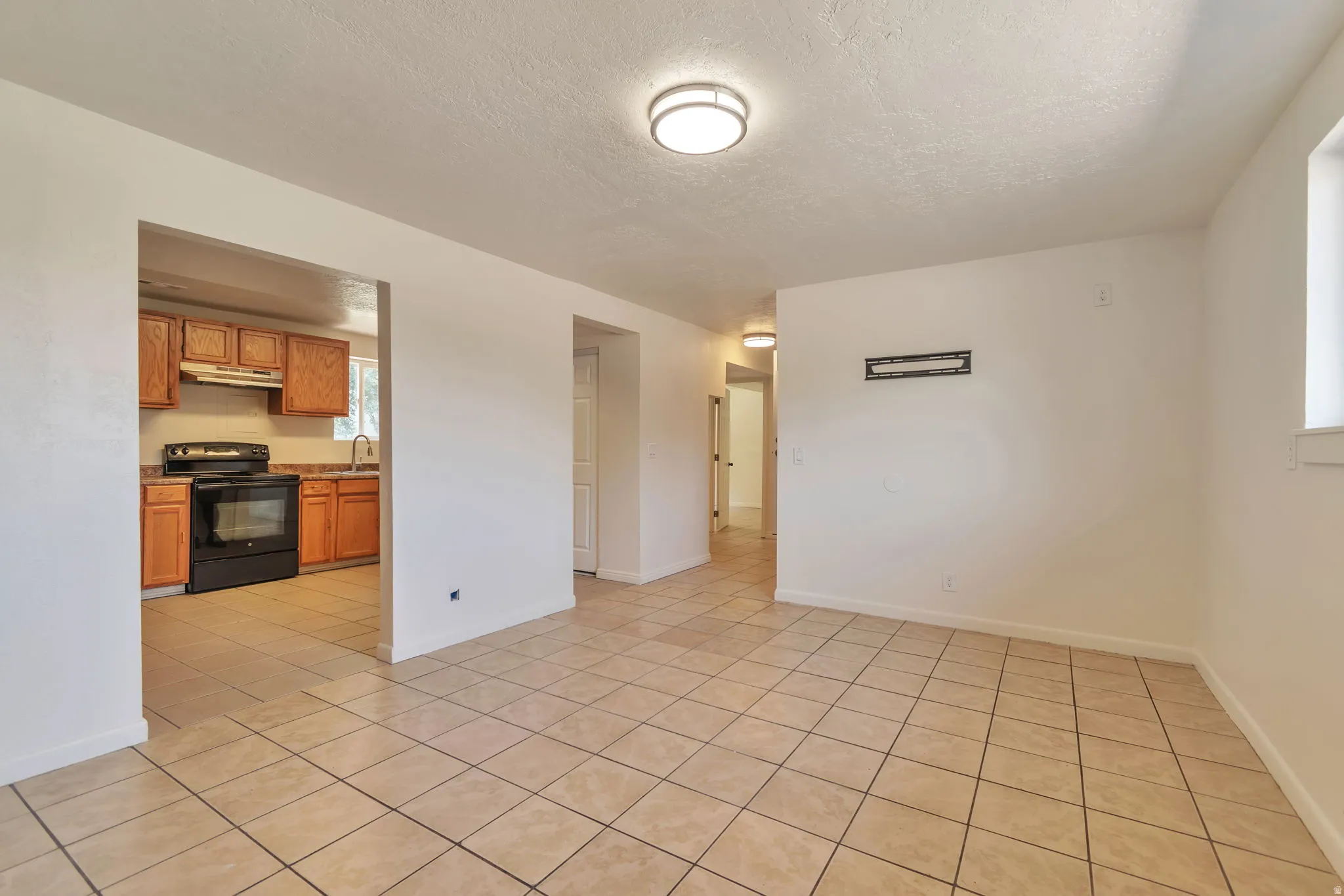 Expansive tile flooring, recessed kitchen appliances, wood-finish cabinetry, and contemporary ceiling lighting
