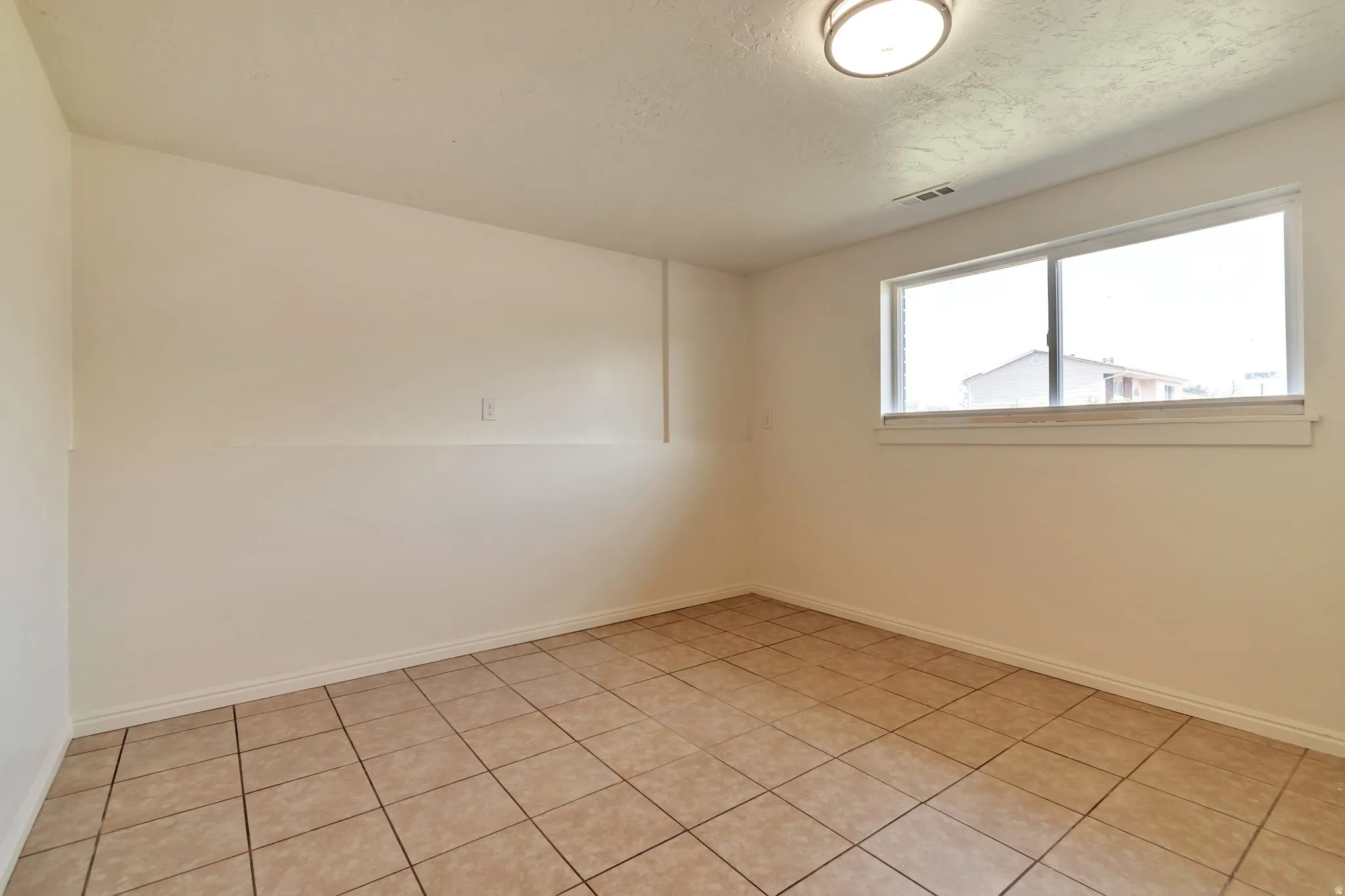 Recessed window with white trim, flush mount ceiling light, and neutral tile flooring