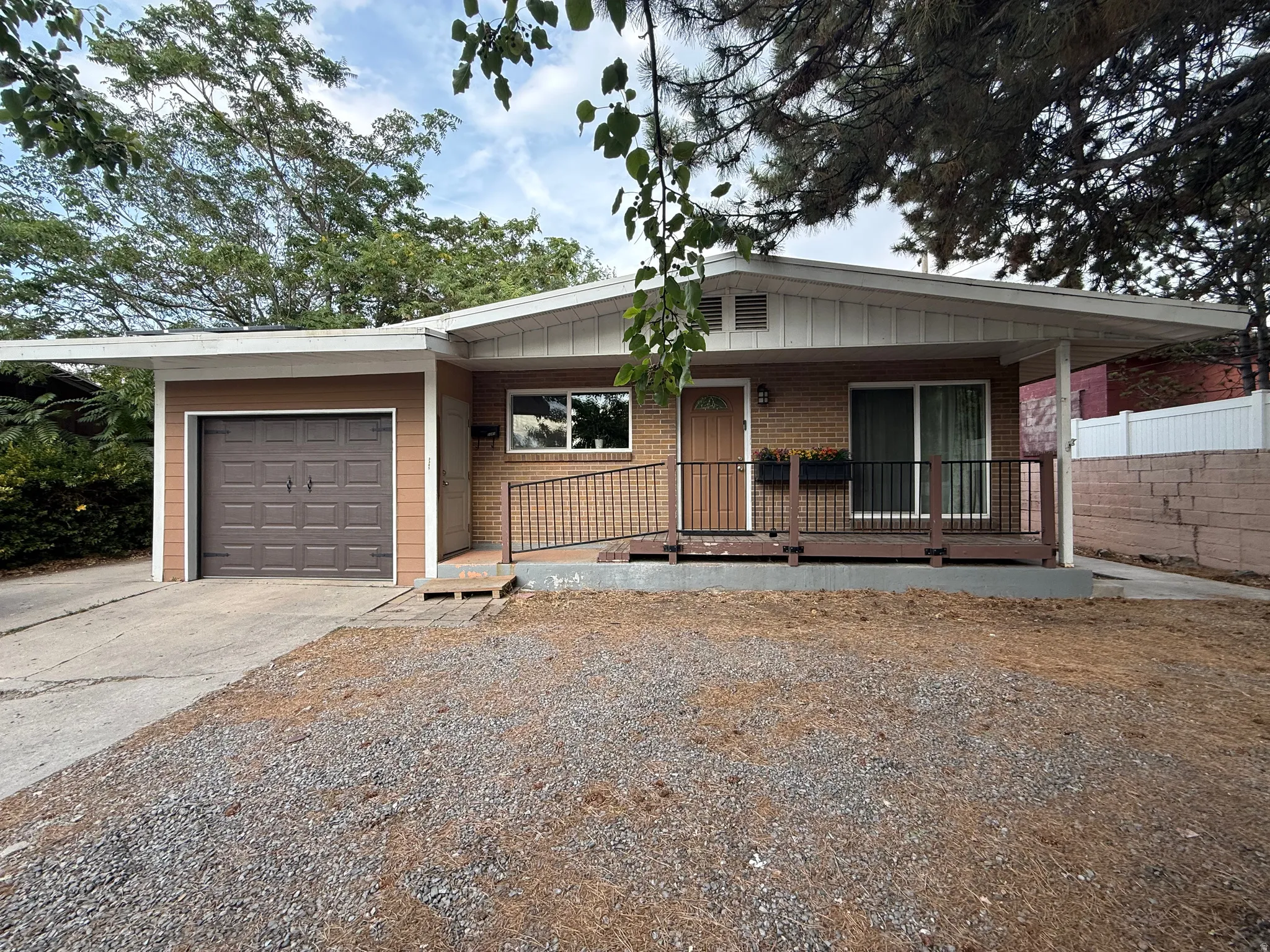 Brick and siding exterior featuring a covered entryway, attached single-car garage, and a front porch with railing