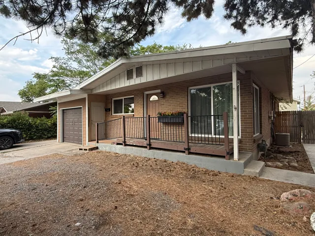 Brick exterior with a covered porch featuring a dark wood floor and black railings