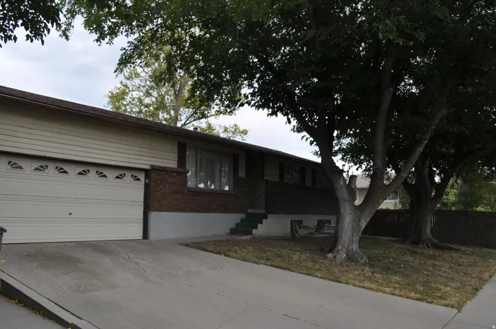 Attached garage with paneled door, brick facade, and concrete driveway