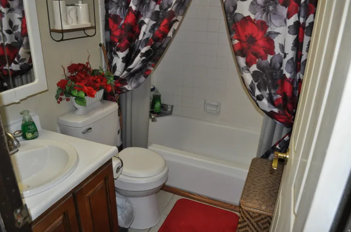 White bathtub with ceramic tile surround, toilet, and a vanity with a white countertop and integrated sink
