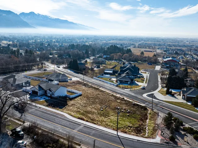 Expansive aerial view showcasing this residential property situated on a curved street with mature landscaping and established neighborhood surroundings