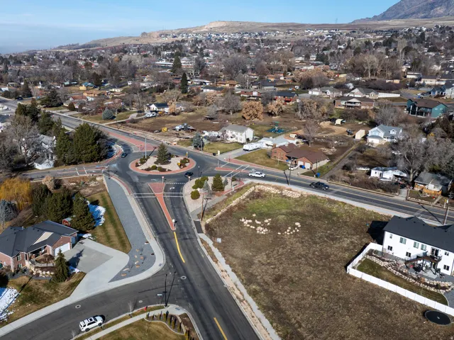Residential neighborhood featuring a prominent roundabout, varied housing styles, and distant mountain scenery