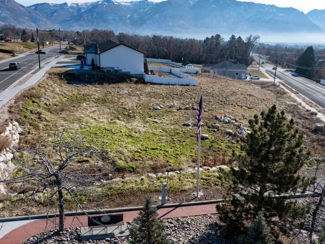 Expansive lot with varied terrain, featuring an adjacent paved road and mountain backdrop