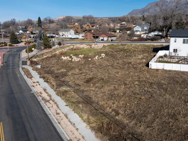 Expansive land parcel featuring direct road frontage, a paved sidewalk, and established hardscaping