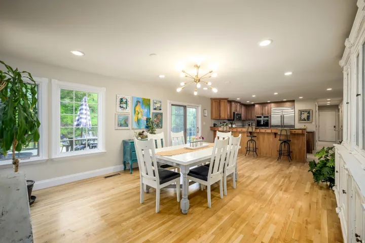 Hardwood flooring throughout, recessed lighting, and a kitchen with wood cabinetry, stainless steel appliances, and a breakfast bar