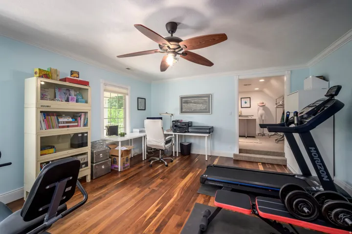 Hardwood flooring, ceiling fan with integrated lighting, built-in shelving, window with natural light, and crown molding