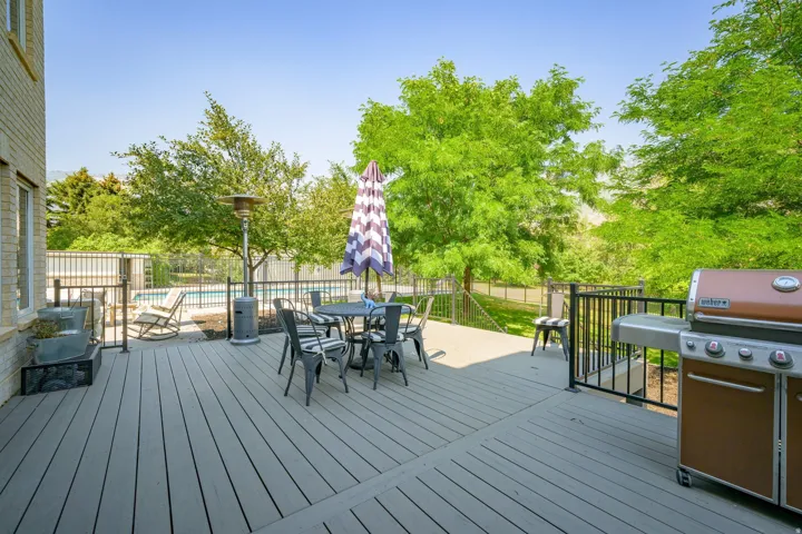 Spacious outdoor deck with composite decking, black metal railings, and a visible swimming pool beyond